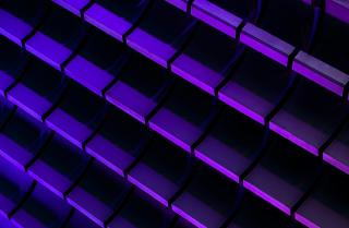 Photograph of neon purple and blue glowing bricks arranged in a 3D pattern against a dark background