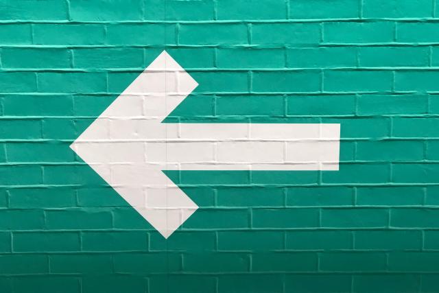 A white arrow on a blue brick wall